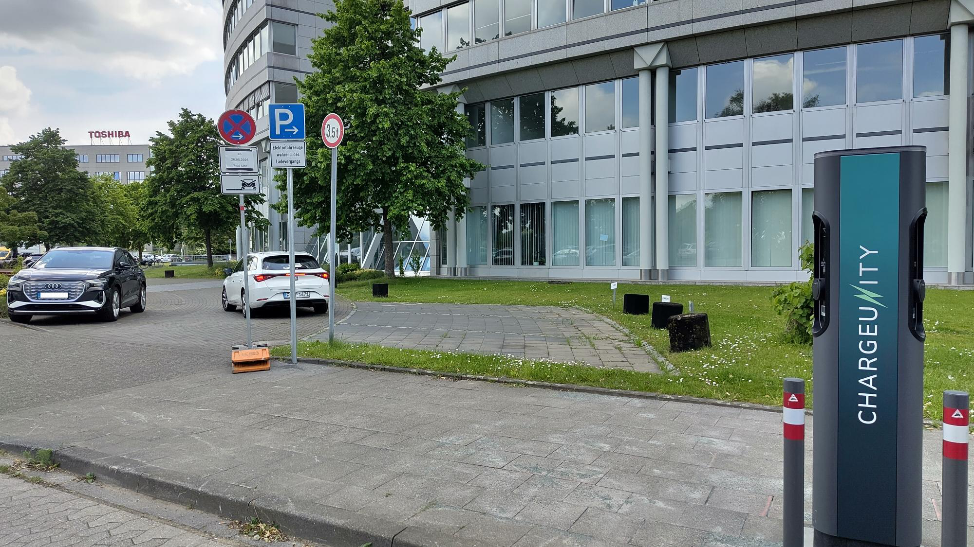 CHARGEUNITY Ladesäule an einer öffentlichen Parkfläche vor einem Bürogebäude